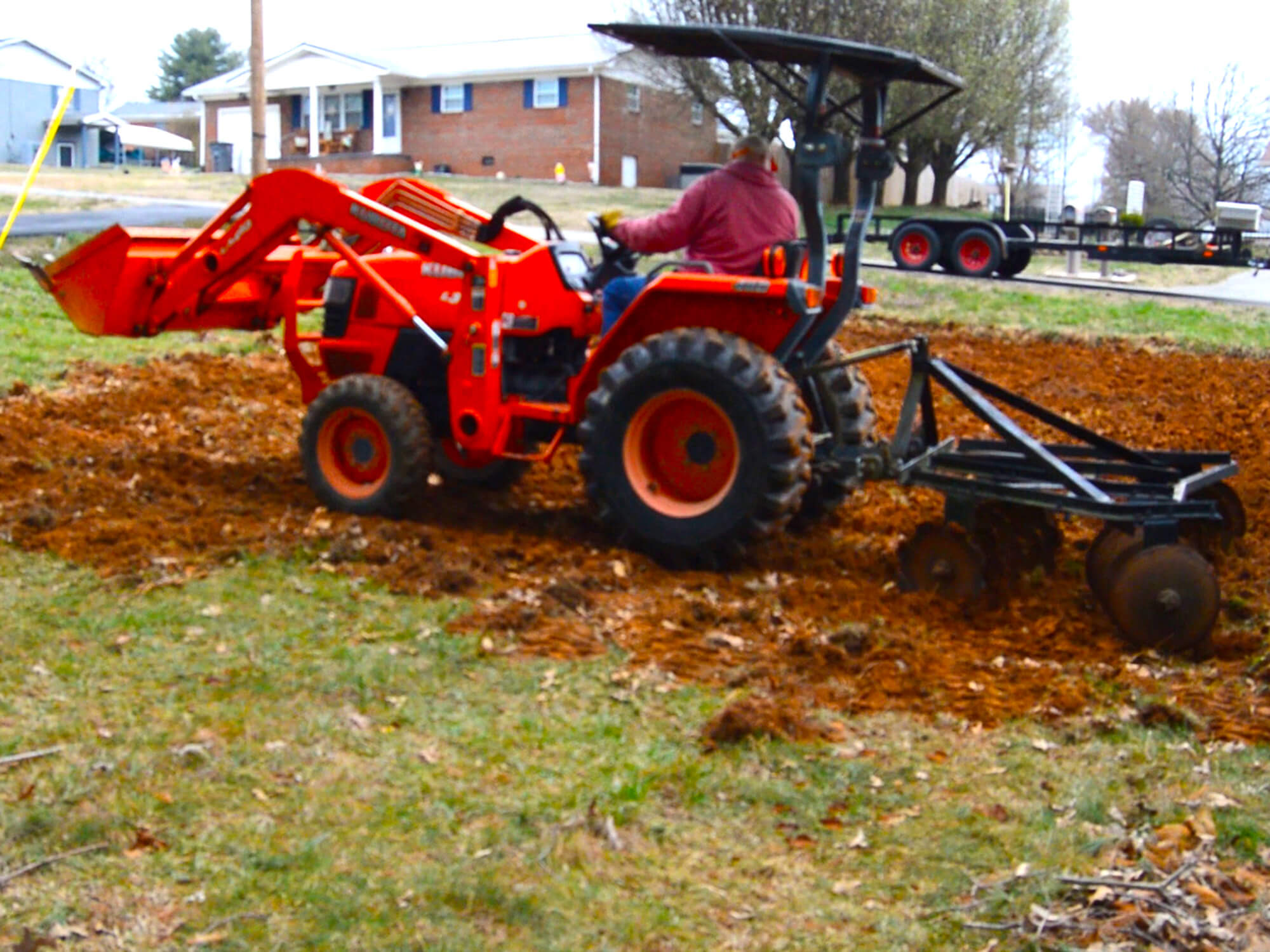 A Kubota subcontract tractor discing an urban garden.