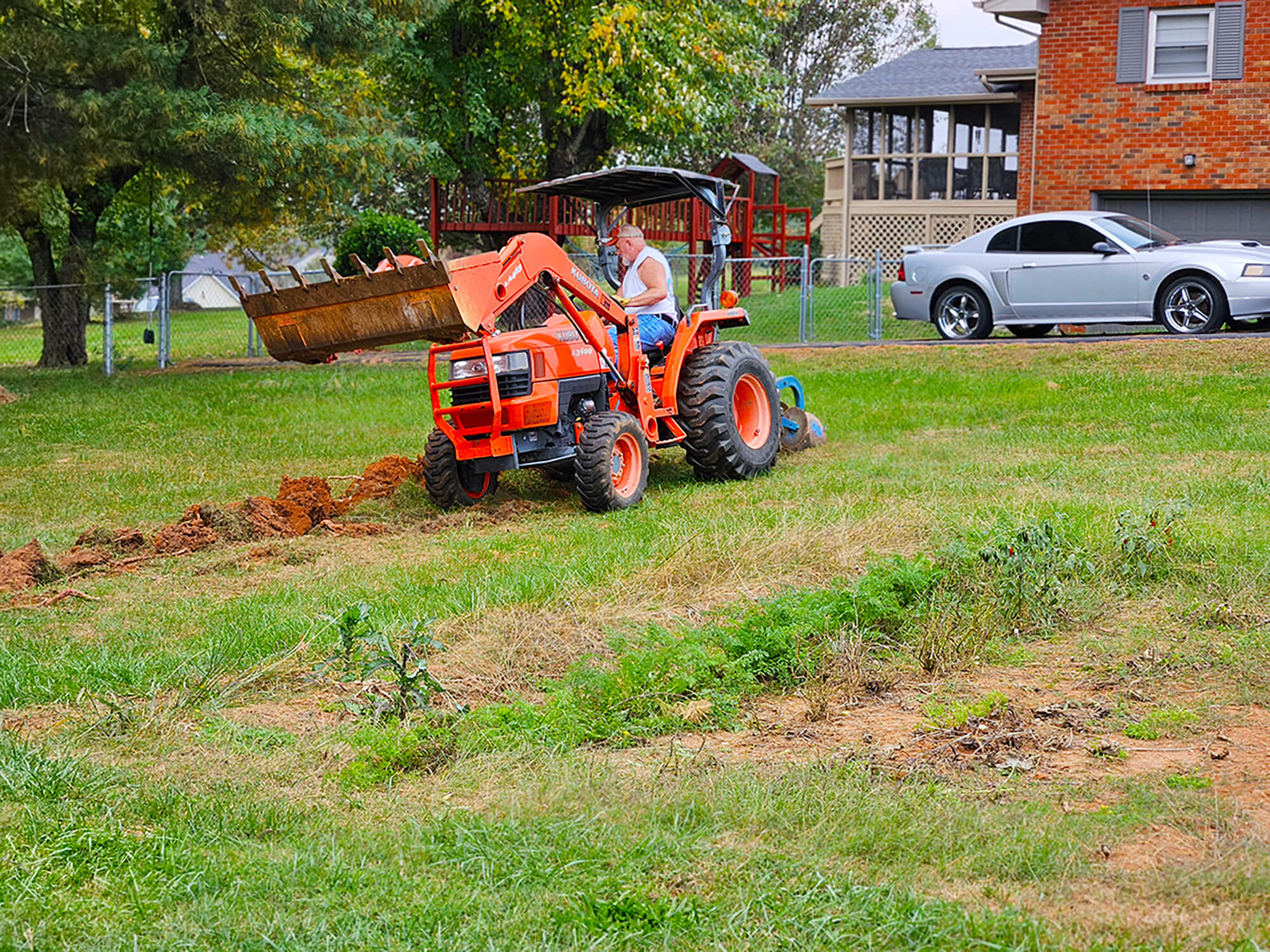 An in ground garden is being cut in as part of an urban garden project by a Kubota subcompact tractor.