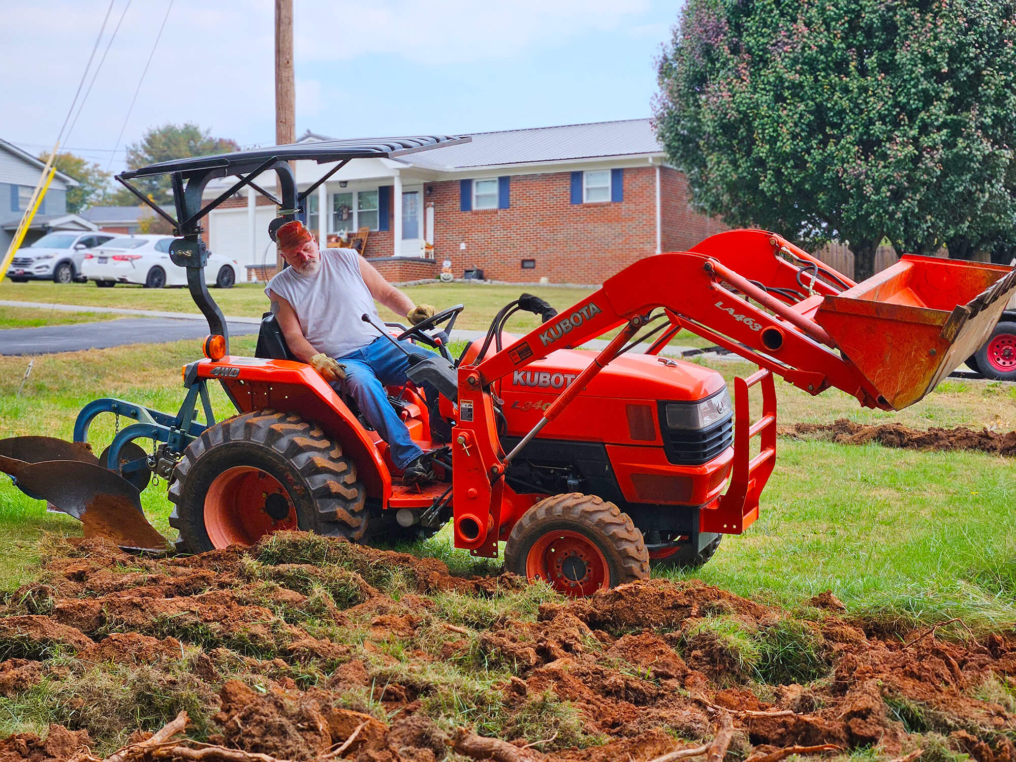 A Kubota subcompact tractor is being used to plow the urban garden.