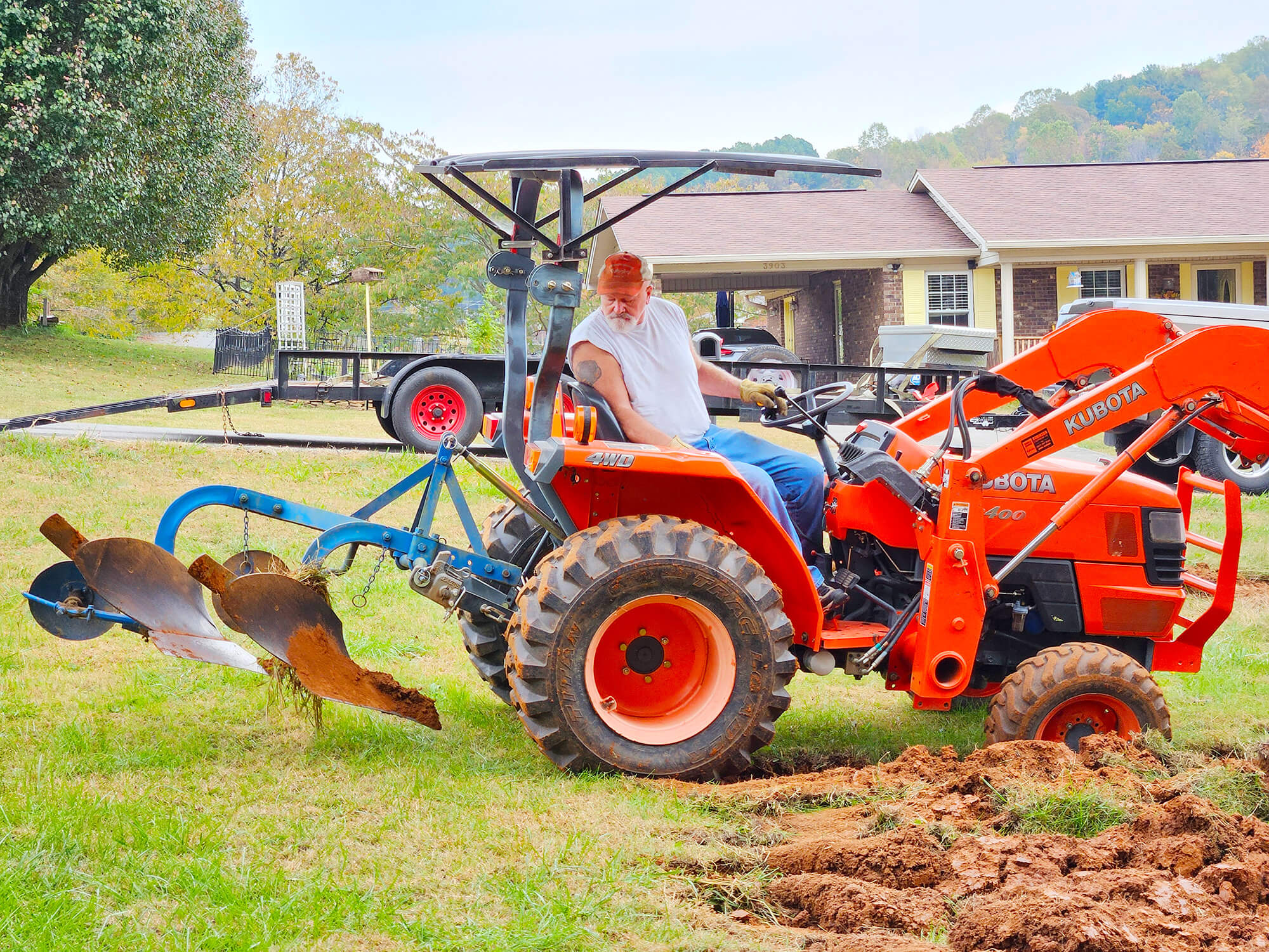 The Kubota subcompact tractor is pulling a double plow to create the urban garden.