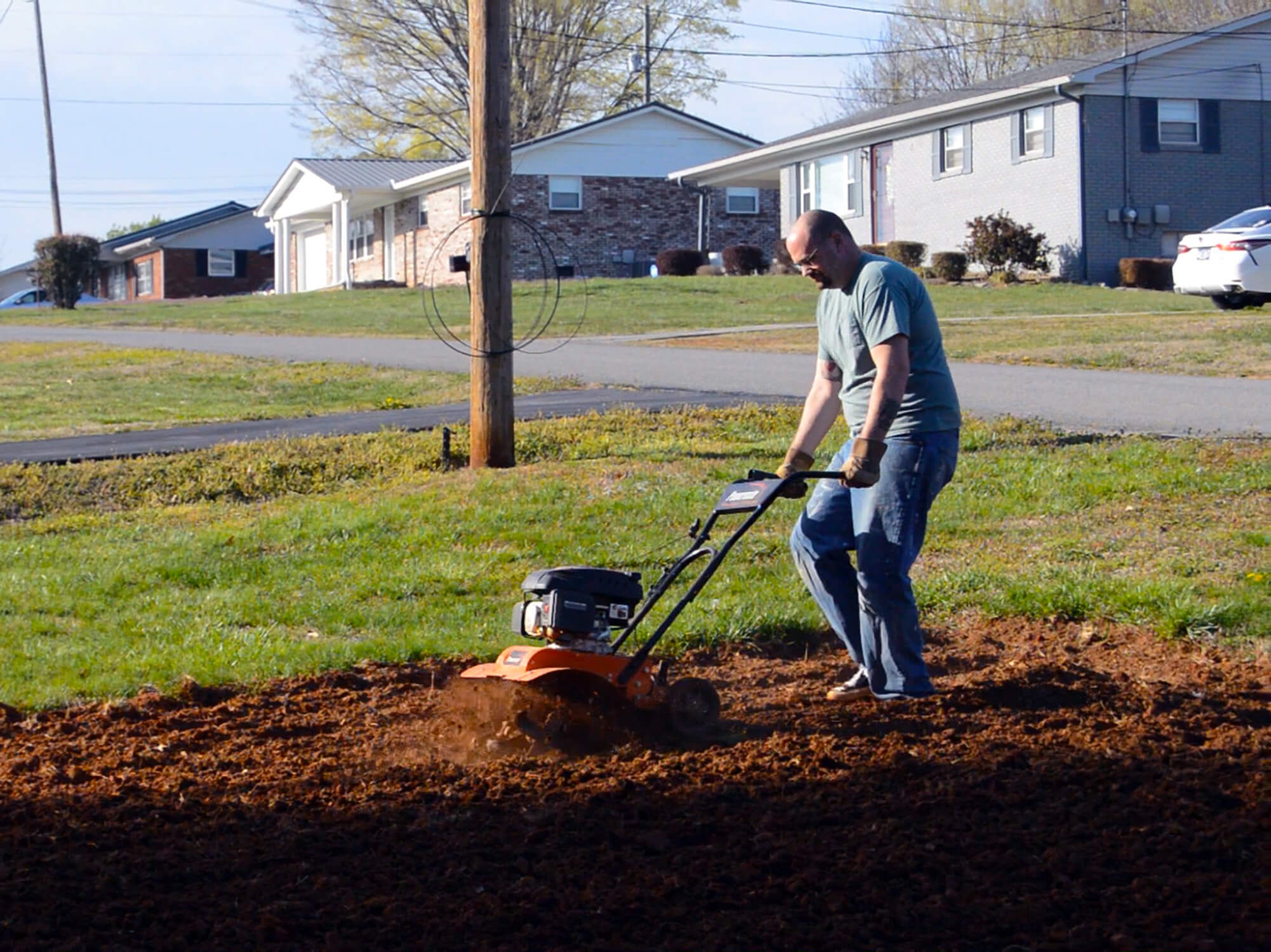 An urban garden being tilled by a walk behind tiller.