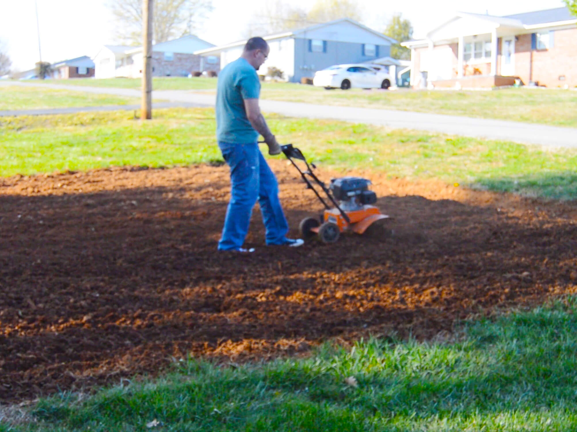 An urban garden being tilled by a walk behind tiller.